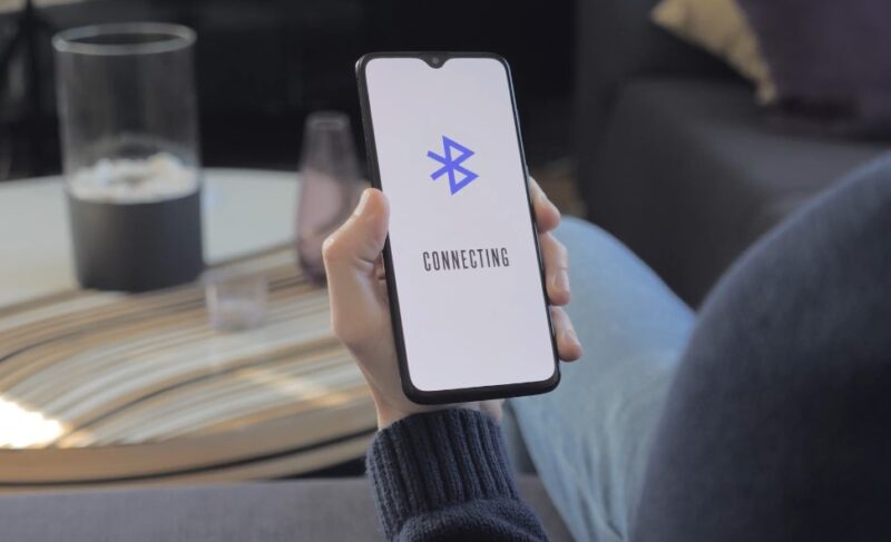 Man holding phone and trying to connect to a bluetooth