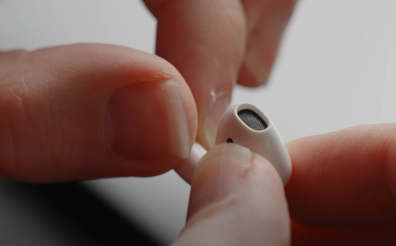 Man holding white airpod with his fingers