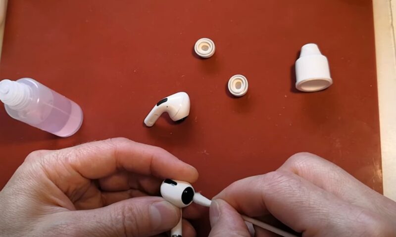 Man cleaning air pods with a cotton swab