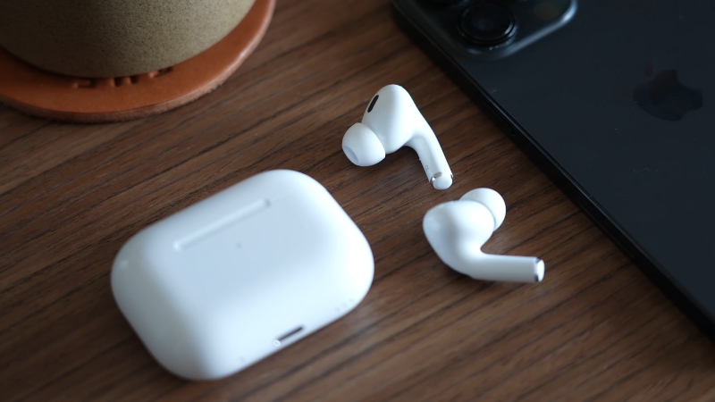 Two AirPods Beside Their Case and An iPhone, with One AirPod Not in The Case